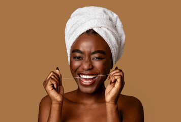 Young black woman using dental floss looking at camera