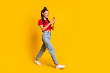 Full length body size view of lovely focused cheerful girl going using device app 5g isolated bright yellow color background