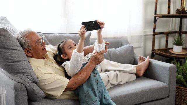 Happy family uncle senior male selfie taking photo with daughter with mobile smartphone on sofa in the living room, Elderly old man patient retired enjoy life concept.