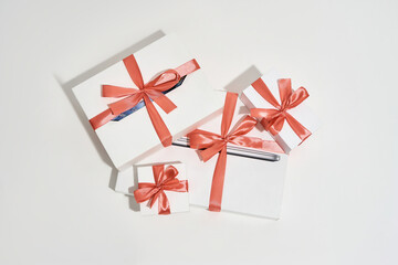 Top view of a pile of gift boxes of different sizes with red bows on white background