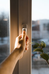 Male hand holding the handle of the window. Man opening (closing) a window. Sun glare on the hand....