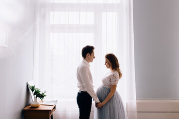 Pregnant woman with husband in front of the window