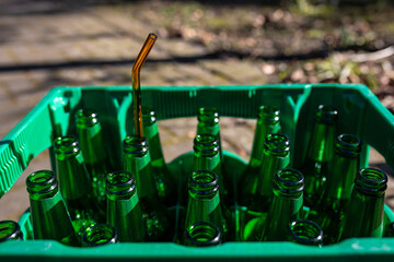Ein Strohhalm steckt in einer leeren Bierflasche in einem Kasten Bier
