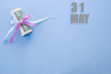 calendar date on blue background with rolled up dollar bills pinned by blue and pink ribbon with copy space. May 31 is the thirty-first day of the month