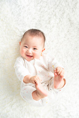 足を持って笑顔で寝転んでいる赤ちゃん