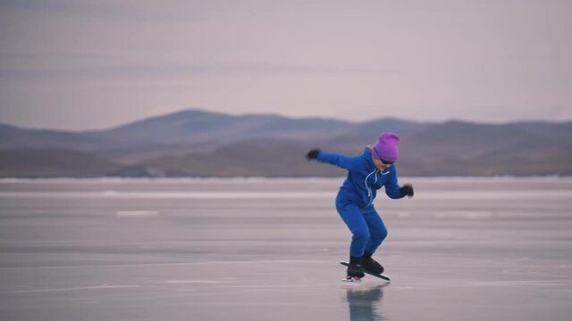 The child train on ice professional speed skating. The girl skates in the winter in sportswear, sport glasses, suit. Children speed skating short long track, kid sport. Outdoor slow motion.