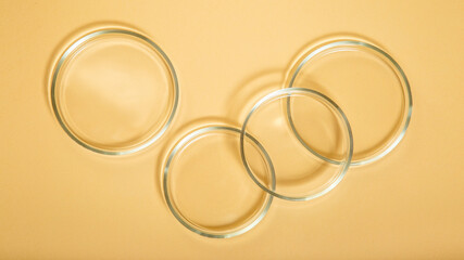 Clean empty petri dishes on beige nude background. Laboratory glassware for bio science, organic skin care products, cosmetic research. Top view cosmetic research circles. Long web banner