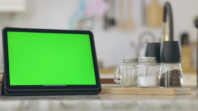 Tablet with green screen chroma key . In kitchen at home.