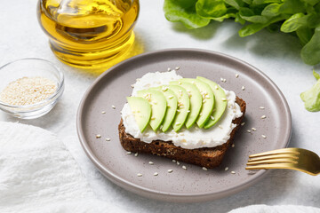 Rye bread toast with avocado and cream cheese on white stone table background. Close up