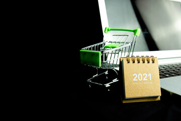 Calendar 2021 with Shopping cart and laptop with dark background. Business Shopping concept. Copy space.