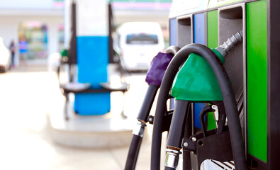 closeup of fuel pumps at a gas station with soft-focus and over light in the background