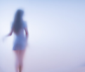 Girl in a short dress behind frosted glass