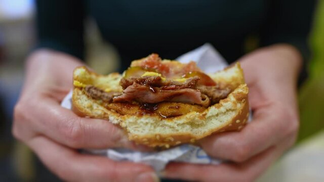 Woman squeezing hamburger in fast food restaurant.