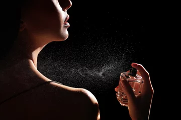 Poster Woman spraying luxury perfume on black background, closeup © New Africa