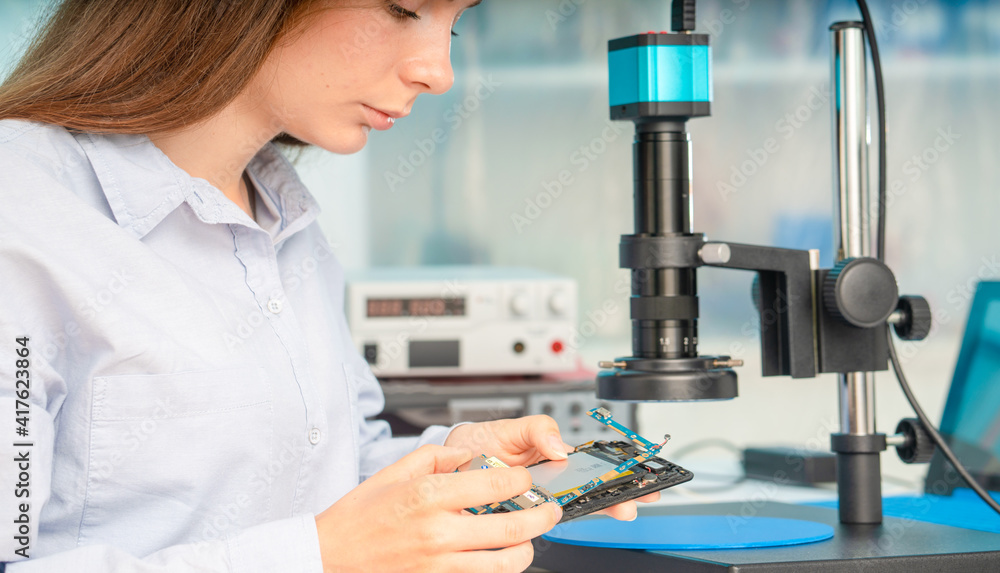 Wall mural a young woman is experimenting with lan on chip devices. microfluidics device