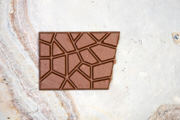 Sweet and delicious whole chocolate bar lies on light stone background photo taken from above in studio