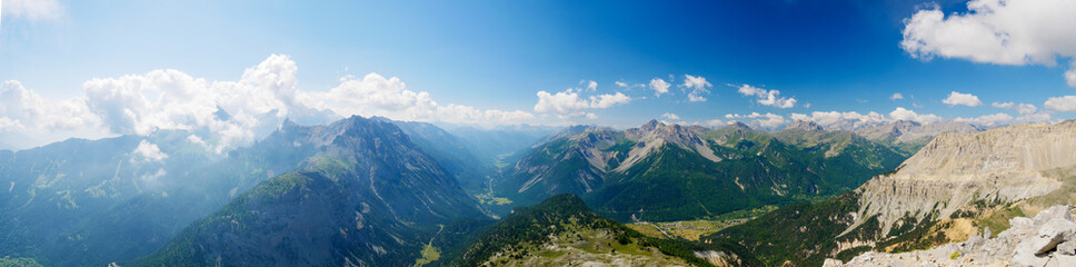 Fototapeta premium High altitude landscape in idyllic uncontaminated environment once covered by glaciers. Summer adventures and exploration on the Italian French Alps. Expansive view from above, clear blue sky.