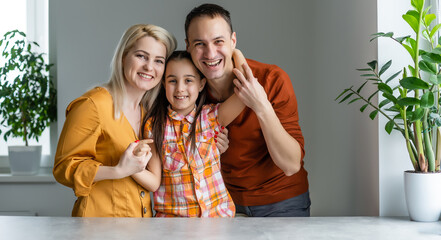 Smiling young parents and their child are very happy, they are at home