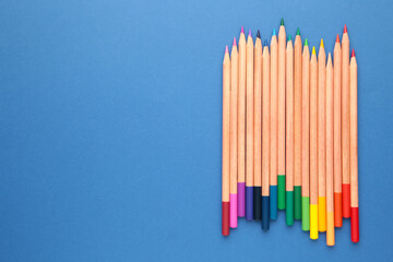 Colored pencils on the blue background with copy space. Top view.