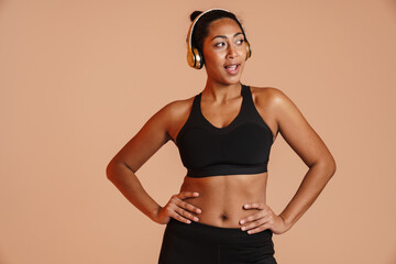 Pleased african american sportswoman posing in wireless headphones