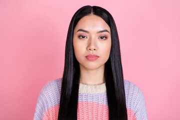 Photo of young beautiful charming serious focused girl with long dark hair in striped sweater isolated on pink color background