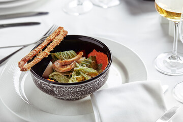 Caesar salad with bread sticks, quail eggs, cherry tomatoes and grilled chicken in plate on white background