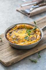 Omlet with mushrooms in a pan on a concrete background. Fritata is an Italian breakfast dish.