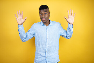 Young african american man wearing a casual shirt standing over yellow background showing and pointing up with fingers number ten while smiling confident and happy