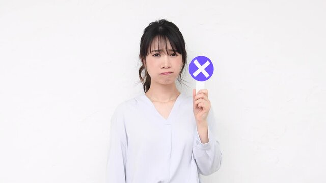 白い壁の前でNGのプラカードを持っている若い女性
