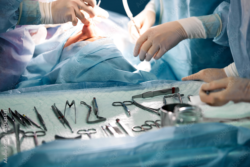 Poster hands of a team of surgeons close-up in the operating room during the operation, sterile instruments