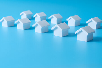 Row of miniature 3D white houses on blue background for real estate property industry