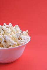 Popcorn in bowl on a red background. Close up. Top view
