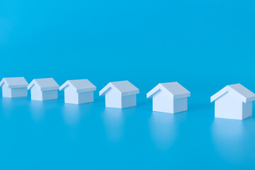 Row of miniature 3D white houses on blue background for real estate property, housing development or community