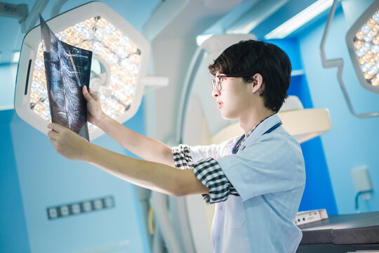 doctor looking at radiological spinal x-ray film for medical diagnosis on patient’s health on spine disease, bone cancer illness, spinal muscular atrophy, medical healthcare concept