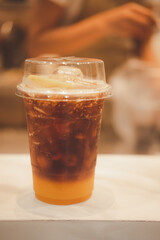 A plastic glass of espresso mixed with craft soda and orange juice and topping with orange slice.