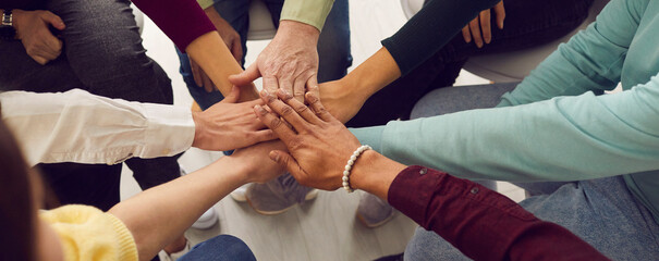 People of different ages and nationalities fold their hands on each other, symbolizing their unity and support. Team of people who are set up for productive work and a positive result. Close up. - obrazy, fototapety, plakaty