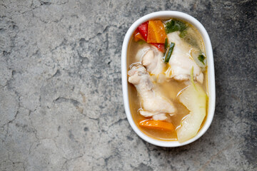 Boiled green soup winter melon with chicken drumsticks and carrot in a white ceramic bowl.