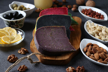 Multi colored gourmet cheese, olives, nuts and sliced lemon. Wine party snacks. Close-up