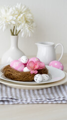 Fototapeta na wymiar Easter lunch. Festive menu. Holiday food decoration. Party catering. Pink color painted eggs in nest served in plate with white Spring flower bouquet tablecloth composition on light background.