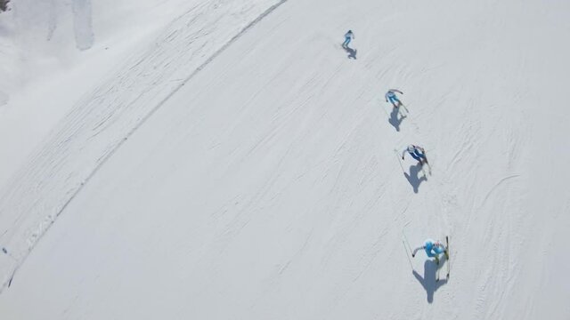 SLOW MOTION: Aerial view of people skiing on mountain. A sports movie camera chases downhill skiers from different shooting angles. ProRes 422, 2k