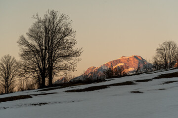Sunset view of mountain peaks in the swiss alps from a farm field in the Glarus valley during winter