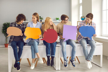 Creative young people, school classmates, college students holding multicolored paper cardboard speech bubbles, exchanging opinion, finding common grounds, interests, ideas. Online youth forum concept