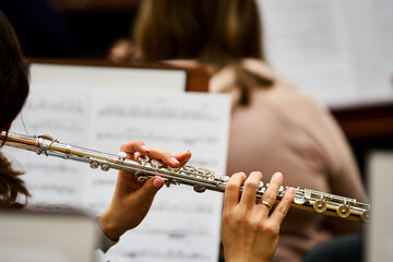 Flute player in orchestra. A woman plays fly. Rehearsal.