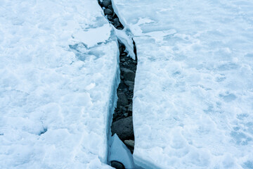 Crack in an glacial ice shelf revealing dry bedrock beneath.
