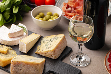 Different types of cheese and wine on gray table