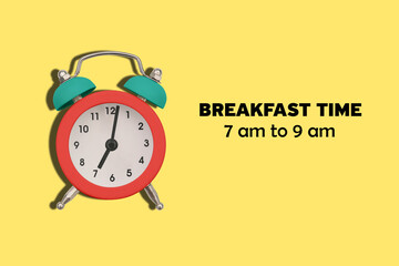 Time for breakfast. The alarm clock shows 7 o'clock in the morning. Old colored alarm clock on a...