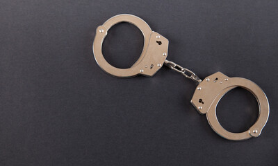 Metal handcuffs on an isolated black background.