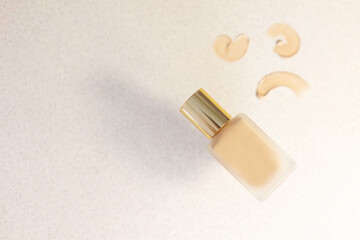 A bottle of makeup foundation on a beige background with tone brush strokes. Foundation selection concept. Copy space