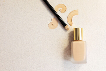 glass bottle with make up foundation on a light background with brush and smears . Copy space