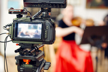 Video camera on  tripod records the image during a string quartet performance.